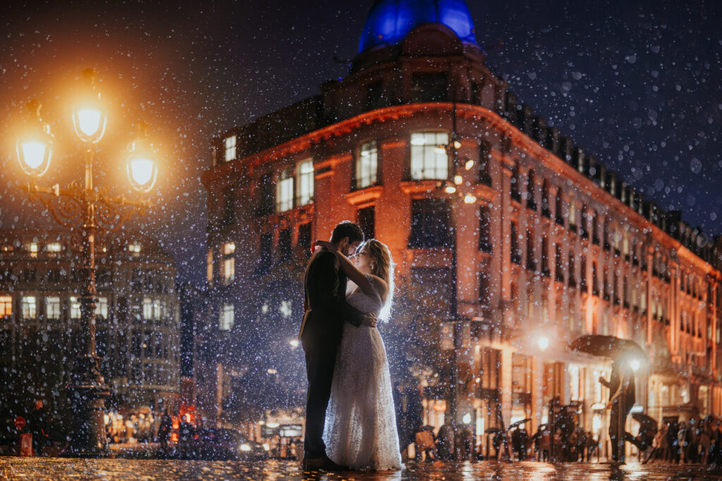 Séance photo de couple de marié devant immeuble sous la pluie